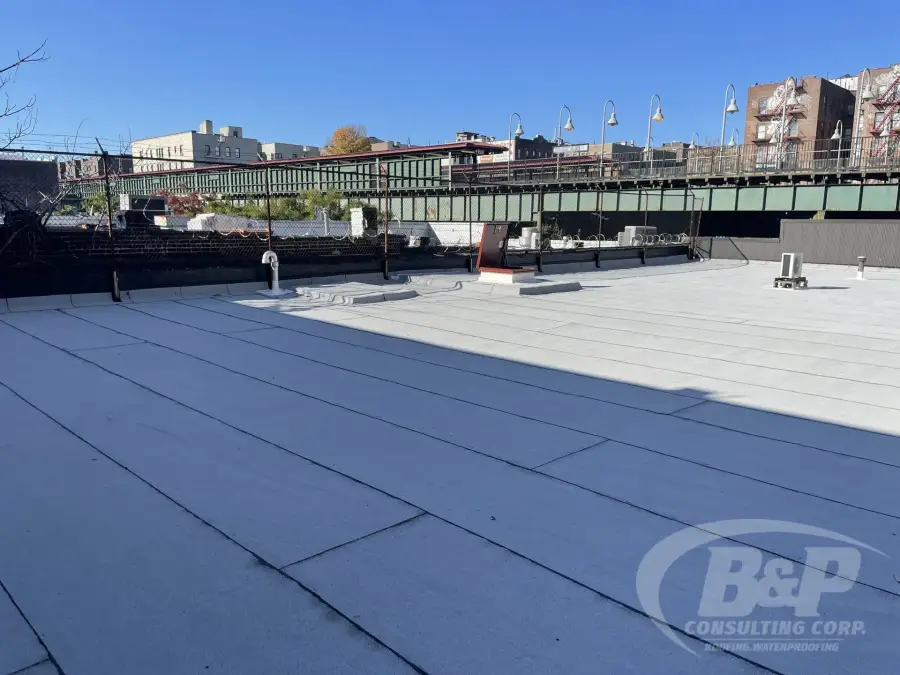 Large commercial flat roof with new membrane next to an elevated train line