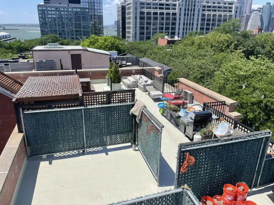 Brooklyn Heights rooftop with new roofing behind dark fence panels