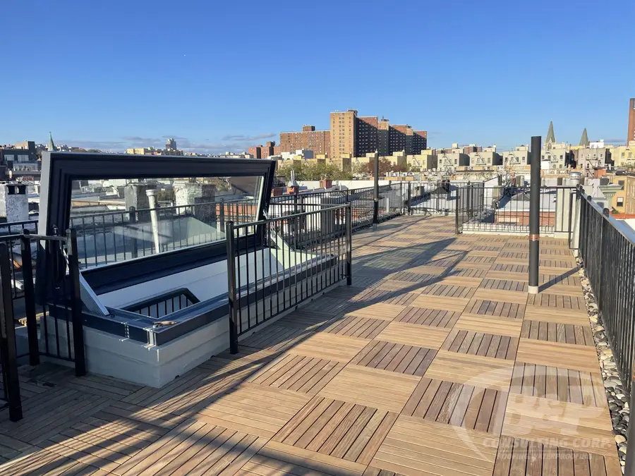 Ipe wood paver rooftop deck with black railings and a skyline view